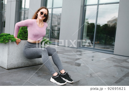 Beautiful fitness girl doing triceps exercises on the street. 92695621