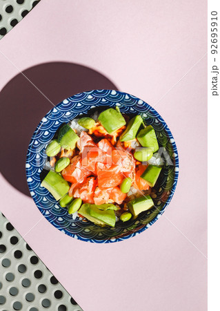 Poke bowl with rice, avocado, edamame beans and smoked salmon. Hard light, deep shadow Poke bowl with rice, avocado, edamame beans and smoked salmon. Hard light, deep shadow 92695910