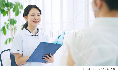 相談を受ける白衣の女性スタッフ 92696356
