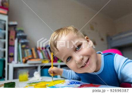 Portrait of cute little blond kid boy enjoy have fun painting with watercolor and brush bright abstract inage on paper at home or kindergarten class. Imagination development children play activity Portrait of cute little blond kid boy enjoy have fun painting with watercolor and brush bright abstract inage on paper at home or kindergarten class. Imagination development children play activity 92696387