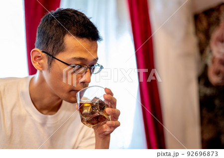 一人で黙々とウイスキーを飲む男性 92696873