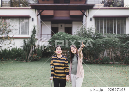 Caregiver take care to senior woman hand holding crutch try to walking at outdoor,Physical therapy concept Caregiver take care to senior woman hand holding crutch try to walking at outdoor,Physical therapy concept 92697163