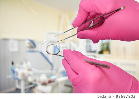 Dentist's hands with tweezers and mouth mirror. Dentist's hands with tweezers and mouth mirror. 92697802