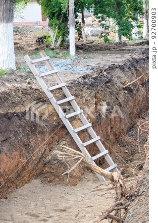 A wooden staircase stands in a deep pit dug for construction work A wooden staircase stands in a deep pit dug for construction work 92700903