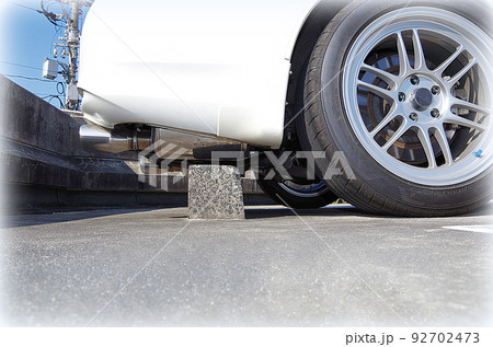 乗用車のバック駐車で車止めとマフラーがギリギリ当たらない状態(イラスト風) 乗用車のバック駐車で車止めとマフラーがギリギリ当たらない状態(イラスト風) 92702473