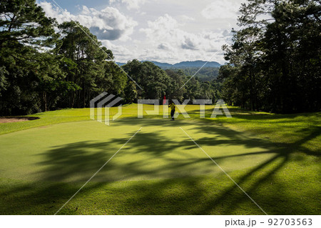 Golfer putting ball on the green golf, lens flare on sun set evening time. 92703563