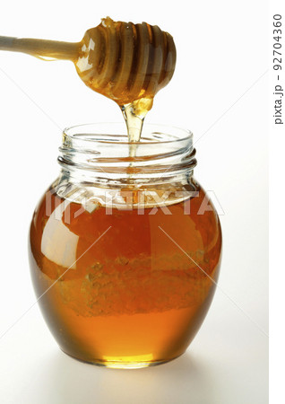 Jar of honey with wooden drizzler on white background 92704360