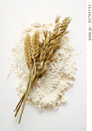 Flour pile with golden ears on white background Flour pile with golden ears on white background 92704732