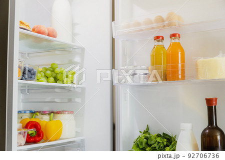 Front View of open two door fridge or refrigerator door filled with fresh fruits and vegetables, full of healthy food items and ingredients inside. Electric Kitchen and Domestic Major Appliances 92706736