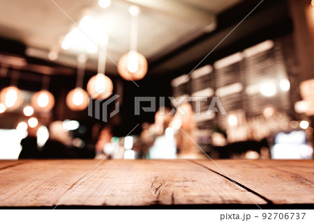 Empty blank wooden old deck table in front of abstract blurred festive background in bar, cafe, pub or restaurant with light spots and bokeh for product montage display of product. Copy space area 92706737