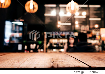 Empty blank wooden old deck table in front of abstract blurred festive background in bar, cafe, pub or restaurant with light spots and bokeh for product montage display of product. Copy space area 92706738