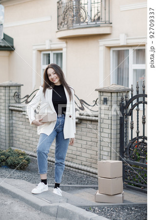 Young woman carrying parcels home, standing with a heap of cardboard boxes. Concept of buying goods online and delivering them home 92709337