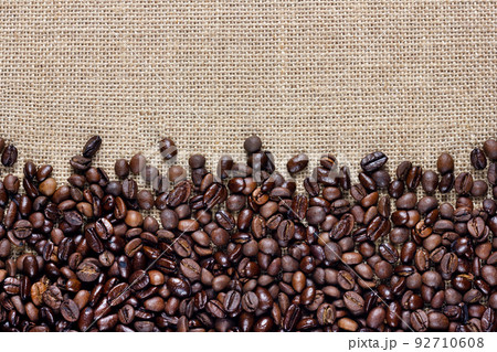 Coffee beans on burlap background. Border design. 92710608