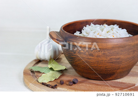 Sauerkraut in clay bowl. Homemade with Carrot and Salad Cabbage on a wooden table. Fermented food. Sauerkraut in clay bowl. Homemade with Carrot and Salad Cabbage on a wooden table. Fermented food. 92710691