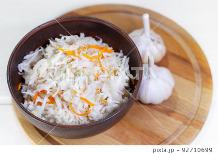 Sauerkraut with carrots in bowl on wooden background. Marinated vegetables. Sauerkraut with carrots in bowl on wooden background. Marinated vegetables. 92710699