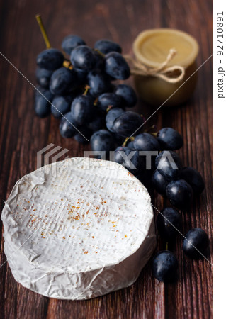 Wheel Camembert with black grapes and honey on wooden table. 92710891