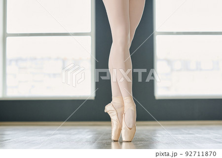 Slim legs of graceful ballet dancer in white tights and beige silk pointe shoes 92711870