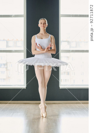 Front view of young successful ballet dancer in white tutu standing on tiptoes 92711872