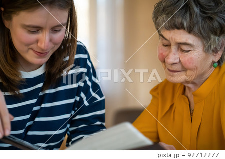 Old woman with her granddaughter look at family photos. 92712277