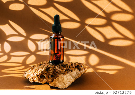 Bottle with pipette made of amber glass, cosmetic product stone podium, background abstract shadows 92712279