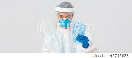 Covid-19, coronavirus disease, healthcare workers concept. Confident serious-looking female asian doctor in personal protective equipment insist patient wearing medical masks, white background Covid-19, coronavirus disease, healthcare workers concept. Confident serious-looking female asian doctor in personal protective equipment insist patient wearing medical masks, white background 92712628
