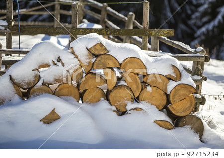 Neatly piled stack of chopped dry trunks wood covered with snow outdoors on bright cold winter sunny day, abstract background, Fire wood logs prepared for winter, ready for burning. Neatly piled stack of chopped dry trunks wood covered with snow outdoors on bright cold winter sunny day, abstract background, Fire wood logs prepared for winter, ready for burning. 92715234