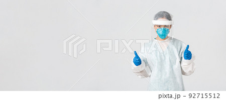 Covid-19, coronavirus disease, healthcare workers concept. Serious-looking confident young asian female doctor, infectionist in personal protective equipment showing thumbs-up, enter dangerious zone Covid-19, coronavirus disease, healthcare workers concept. Serious-looking confident young asian female doctor, infectionist in personal protective equipment showing thumbs-up, enter dangerious zone 92715512
