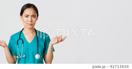Healthcare workers, preventing virus, quarantine campaign concept. Close-up of confused and puzzled asian female physician in scrubs having complicated problem, raising hands and shrugging Healthcare workers, preventing virus, quarantine campaign concept. Close-up of confused and puzzled asian female physician in scrubs having complicated problem, raising hands and shrugging 92715630