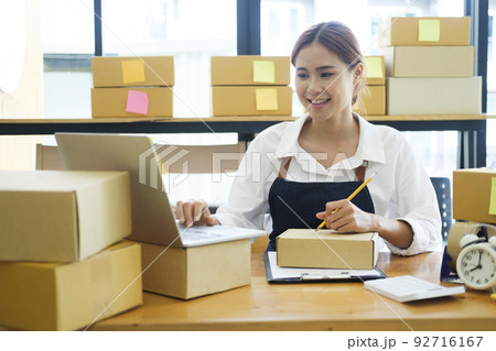 Asian businesswoman Start up small business owner writing address on cardboard box a. 92716167