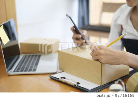 Close up Young Asian businesswoman start up small business owner writing address on cardboard box a. 92716169