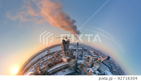 Aerial view from high altitude of little planet earth with cement factory high concrete structure and tower crane at industrial production area in evening. Manufacture and global industry concept 92716304