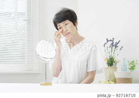 リビングで鏡を見て悩むシニア女性 リビングで鏡を見て悩むシニア女性 92716710