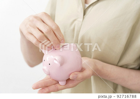 貯金箱に硬貨を入れるシニア女性の手元 白バック 貯金箱に硬貨を入れるシニア女性の手元 白バック 92716788