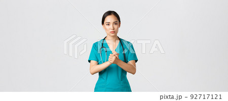 Covid-19, healthcare workers, pandemic concept. Hopeful serious-looking asian nurse, doctor asking something with concerned face, clench hands together in support during coronavirus, white background 92717121