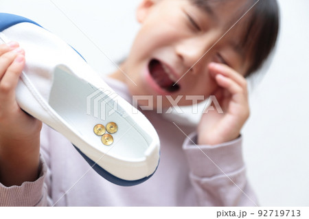 上履きに画鋲が入っていてショックを受ける小学生の女の子 92719713
