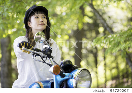 バイク女子イメージ　森でバイクにまたがる若い女性 92720007