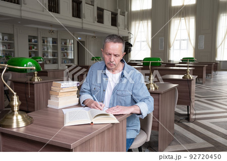 Portrait of caucasian Senior man working with book in public library. Adult student at the library 92720450