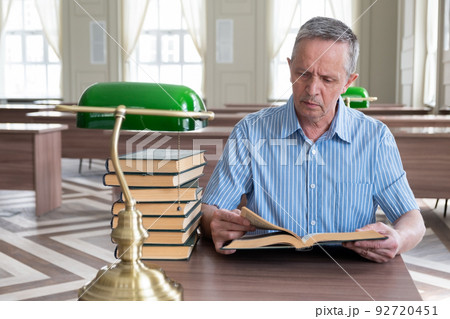 Portrait of caucasian Senior man working with book in public library. Adult student at the library 92720451