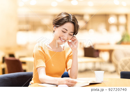 カフェで音楽を聴きながら読書するミドルの女性 カフェで音楽を聴きながら読書するミドルの女性 92720740