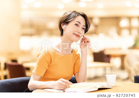 カフェで音楽を聴きながら読書するミドルの女性 92720745