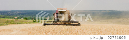 combine mower mechanism cuts spikelets wheat. Agricultural harvesting work. harvester moves field and mows ripe wheat. large harvester collects grain sunny weather. agricultural business. photo banner combine mower mechanism cuts spikelets wheat. Agricultural harvesting work. harvester moves field and mows ripe wheat. large harvester collects grain sunny weather. agricultural business. photo banner 92721006