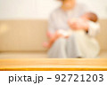 ソファーで赤ちゃんをあやす母親　テーブルの商品背景 92721203