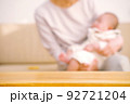 ソファーで赤ちゃんをあやす母親　テーブルの商品背景 92721204