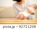 ソファーで赤ちゃんをあやす母親　テーブルの商品背景 92721206