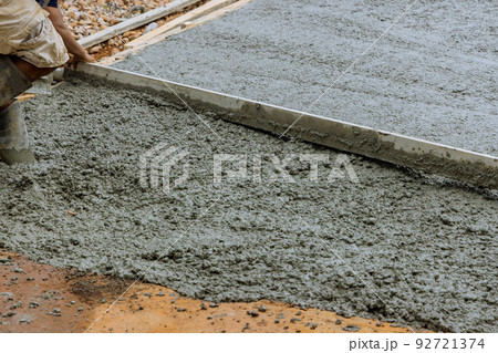 Working on pouring cement a new concrete driveway at a residential home Working on pouring cement a new concrete driveway at a residential home 92721374