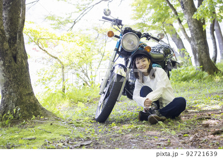 バイク女子イメージ　湖畔でバイクと並ぶ若い女性 92721639