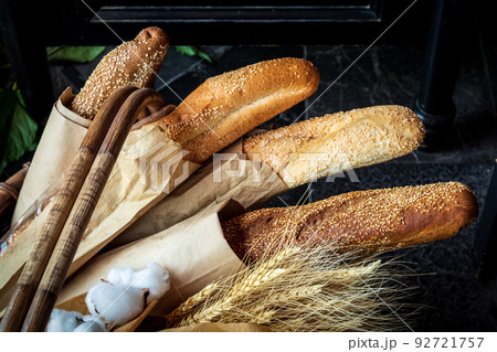 Freshly baked bread lies in a wicker basket. Several different fresh loaves in eco-package along with ears of wheat 92721757