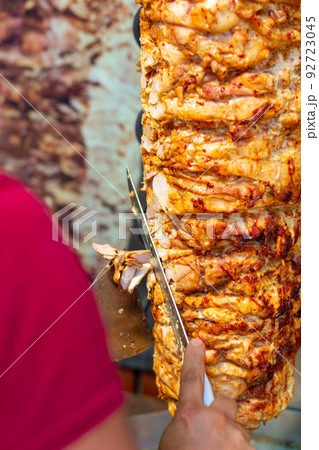 Chef cutting with doner knife Traditional Turkish Doner Kebab meat. 92723045