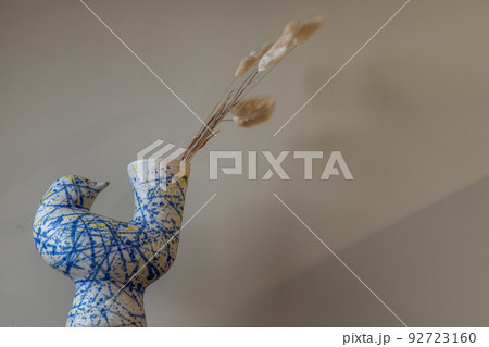 Dried flowers in beautiful ceramic blue vase on wall of living room. Dried flowers in beautiful ceramic blue vase on wall of living room. 92723160