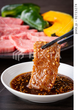 焼肉をタレをつけて食べる 92723274